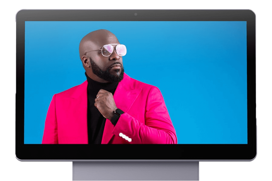 The front of the Elys Workstation with a vivid blue screen and a man wearing a pink blazer, black turtle neck, and aviator sunglasses.